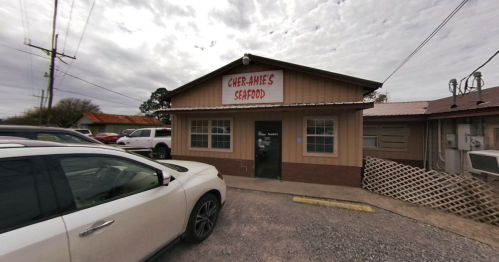A seafood restaurant with a sign reading "Cher-Aine's Seafood," featuring a parking area and cloudy sky.