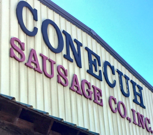 Sign for Conecuh Sausage Co., Inc. against a clear blue sky.