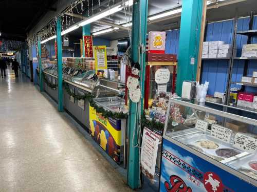 A colorful food stall area in a market, featuring ice cream freezers and festive decorations along the walls.