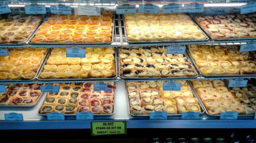 A display case filled with various baked pastries, including fruit tarts and cream-filled treats, neatly arranged on trays.