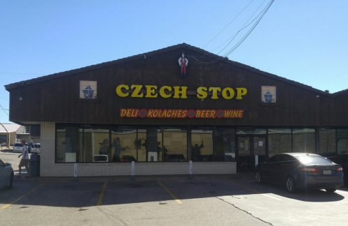 Exterior of Czech Stop, a deli featuring kolaches, beer, and wine, with a wooden facade and colorful signage.