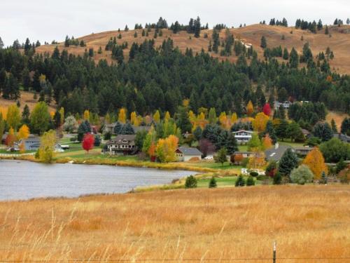 A scenic view of a lakeside community surrounded by colorful autumn trees and rolling hills.