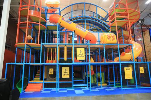 Colorful indoor play structure with slides and climbing areas, designed for children aged 9 and under.