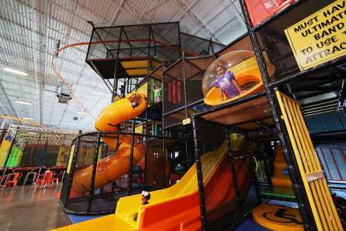A colorful indoor play structure with slides and climbing areas, featuring children playing and exploring.