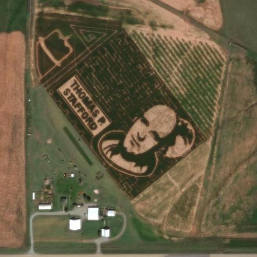 Aerial view of a corn maze featuring a portrait and the name "Thomas P. Stafford" carved into the field.