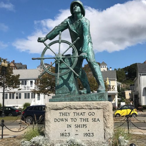A bronze statue of a sailor at a ship's wheel, commemorating those who went to sea, with the years 1623-1923 inscribed.