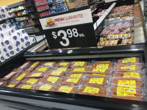 Display of packaged meat products in a grocery store, priced at $3.98 each, with a fresh guarantee sign.