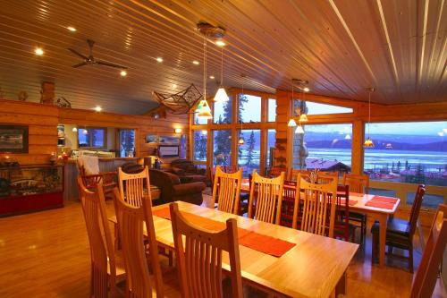 Cozy wooden dining area with large windows overlooking a scenic view, featuring a long table and comfortable seating.