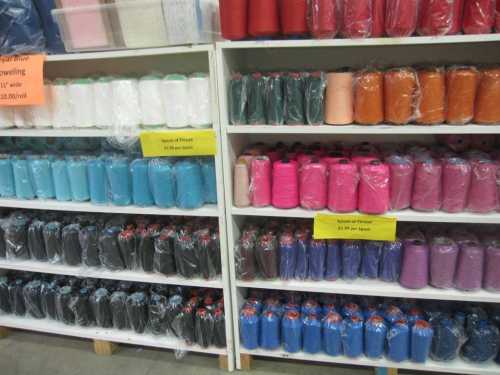 Shelves filled with colorful spools of thread in various shades, neatly packaged and organized.