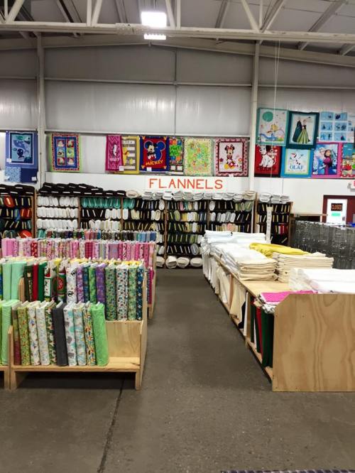 A fabric store interior showcasing colorful flannel rolls and quilt displays on the walls.