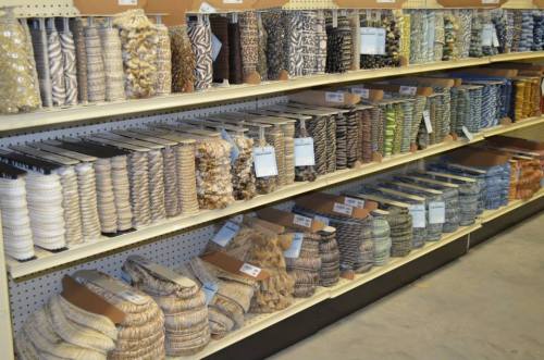 A variety of decorative ribbons and trims displayed on shelves in a craft store.
