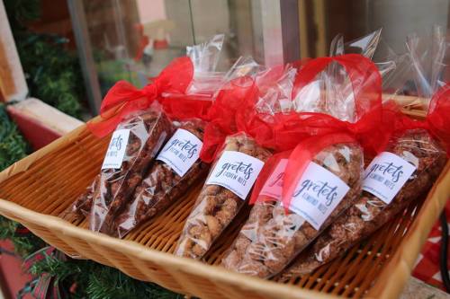 A basket filled with assorted baked goods, each wrapped in clear plastic with red ribbons and labeled "Gretes."