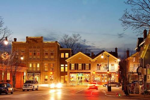 A charming town square at dusk, featuring historic buildings and festive lights, with cars passing by.
