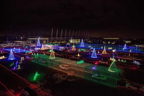 Aerial view of a festive light display featuring colorful illuminated trees and decorations in a dark setting.