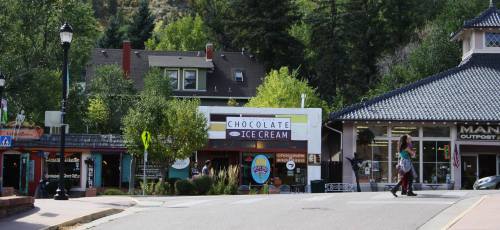 A quaint street scene featuring shops, including a chocolate ice cream store, surrounded by trees and buildings.