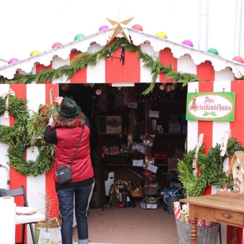 A festive market stall with red and white stripes, decorated with greenery and a star, and a person taking a photo.