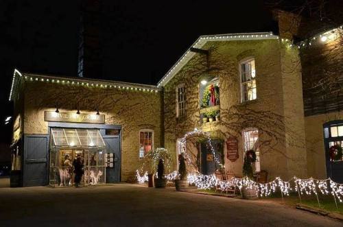 A charming building decorated with festive lights and wreaths, bustling with visitors on a cozy winter night.