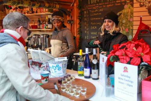 A festive market scene with a vendor serving wine tastings, surrounded by holiday decorations and customers.