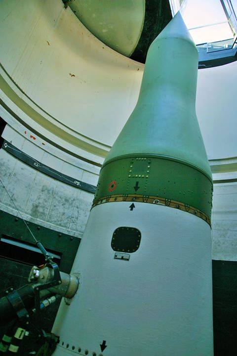 A close-up view of a missile inside a cylindrical structure, with a clear sky visible through the top opening.