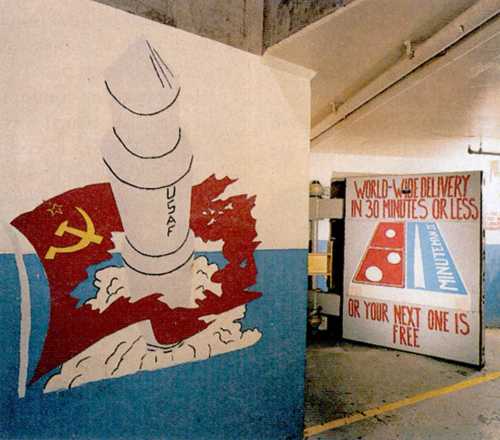 Mural depicting a missile over a map of the UK, with a humorous delivery slogan on a nearby wall.