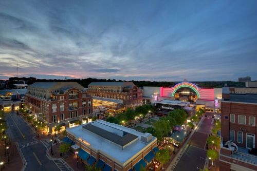 Aerial view of a vibrant shopping district at dusk, featuring colorful lights and a mix of modern and historic architecture.
