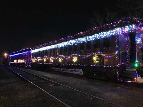 A train car decorated with colorful lights, glowing against a dark night sky.