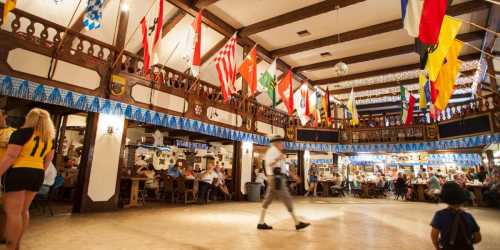 A lively indoor space decorated with flags, featuring people dining and socializing in a festive atmosphere.