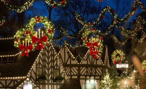 Festively decorated buildings with wreaths, bows, and lights, set against a twilight sky.
