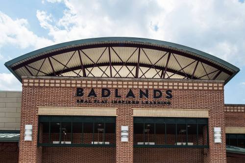 Exterior of the Badlands facility, featuring a brick facade and a large, curved roof under a cloudy sky.