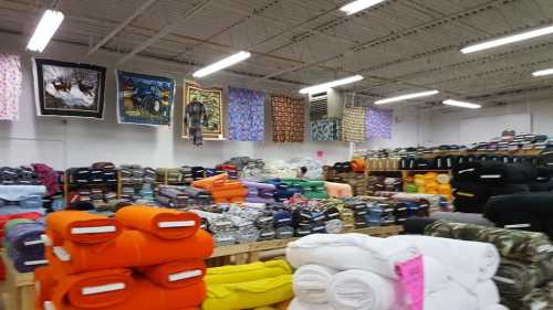 A spacious store interior filled with colorful blankets and quilts stacked on shelves and displayed on walls.