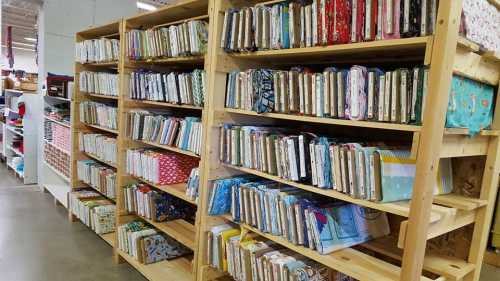 A wooden shelving unit filled with neatly organized fabric swatches in various colors and patterns.