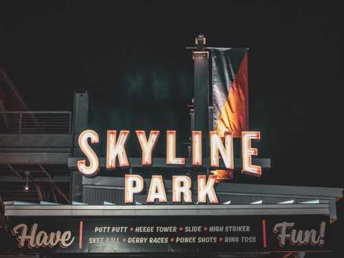 Neon sign for Skyline Park featuring various attractions like putt putt, slide, and ring toss against a dark background.