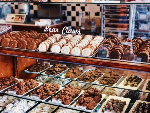 A display case filled with various cookies and pastries, including bear claws and chocolate-covered treats.