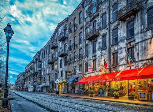 Historic street scene featuring a candy store, vintage buildings, and a cloudy sky in a charming urban setting.