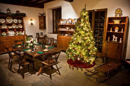 Cozy dining room decorated for Christmas, featuring a lit tree, festive table setting, and vintage wooden furniture.