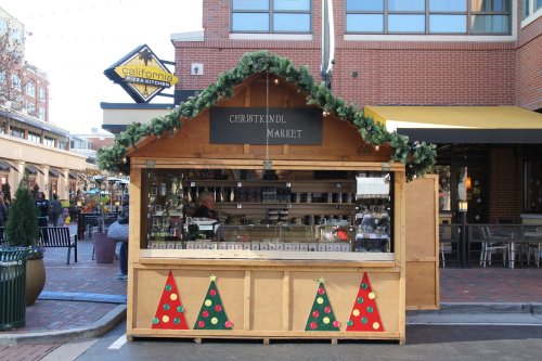 A wooden market stall decorated for Christmas, featuring festive greenery and red and green triangle patterns.