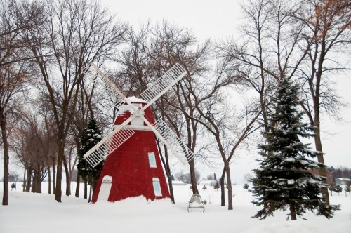 A red windmill surrounded by snow-covered trees in a winter landscape.