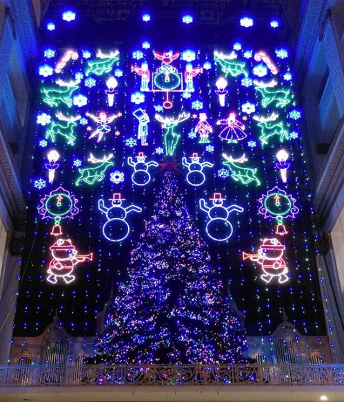 A vibrant holiday display featuring a large Christmas tree surrounded by colorful lights and festive decorations.