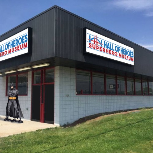 Exterior of the Hall of Heroes Superhero Museum, featuring a Batman statue in front of the building.