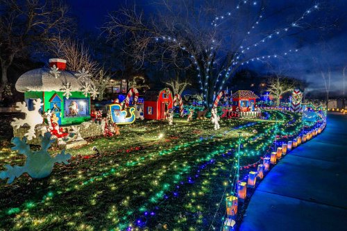 A festive display of colorful Christmas lights and decorations in a park, featuring whimsical holiday scenes.