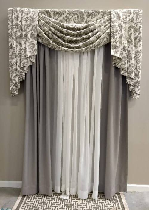 Elegant curtain display featuring a patterned valance and sheer drapes in gray and white tones.