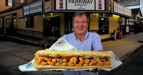 A man holds a giant shrimp po' boy sandwich outside Parkway Bakery & Tavern.