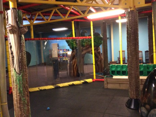 Indoor play area featuring colorful structures, climbing elements, and safety barriers.