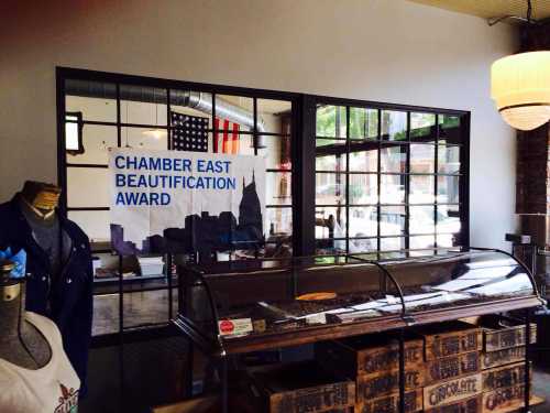 Interior view of a shop featuring a "Chamber East Beautification Award" banner and a display case.