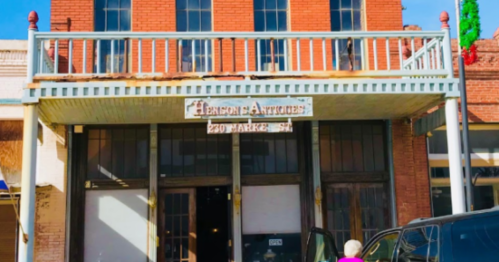 Exterior of Henson Antiques building with a sign, featuring a balcony and festive decorations.