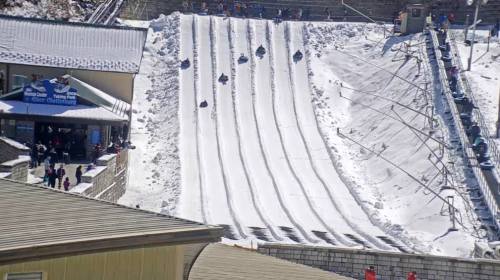 A snowy hill with multiple lanes for tubing, filled with people enjoying winter activities.