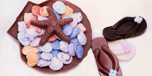 A plate of colorful chocolate candies shaped like seashells, with a starfish and flip-flop chocolates beside it.