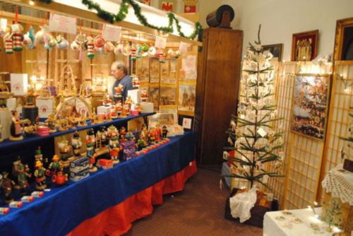 A festive market stall decorated with ornaments, crafts, and a small Christmas tree in a cozy setting.