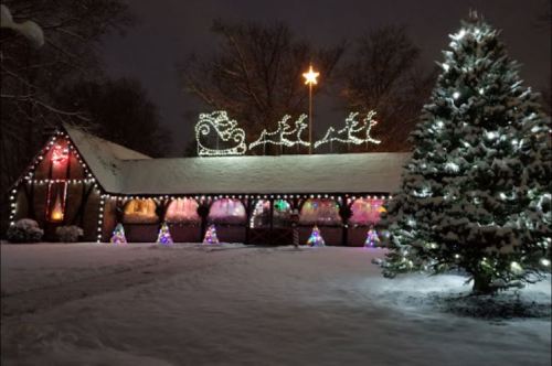 A snowy scene featuring a decorated building with Christmas lights and a large tree, topped with a star.