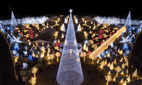 Aerial view of a festive holiday light display featuring a large illuminated Christmas tree and colorful decorations.